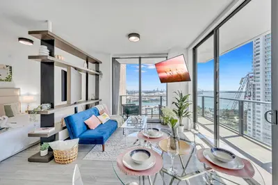 a living room with a blue couch and glass tables at Mesmerizing Water Views Corner Condo in Miami
