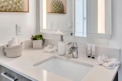 a white bathroom with a sink and a mirror at Mesmerizing Water Views Corner Condo in Miami