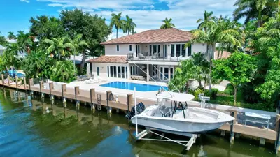 a house with a boat docked at a dock at Elegant Waterfront Estate 6BR- 6.5BA in Fort Lauderdale