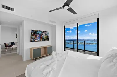 a white bedroom with a bed and a tv at Lux Downtown Miami w Free Parking in Miami