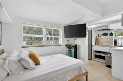 a white bedroom with a bed and a kitchen at Fort Lauderdale airport and Dania Pointe shopping 5 min away in Fort Lauderdale