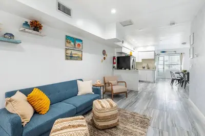 a living room with a blue couch and a kitchen at Ocean Views! Steps from Dining, Shopping, Las Olas in Fort Lauderdale