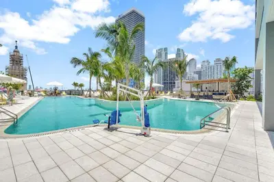 a large swimming pool with palm trees and buildings at Modern 1BR Apartment with Pool in Miami
