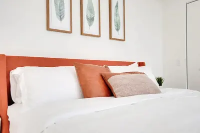 a white bed with brown and white pillows on it at Miami Paraiso- Rooftop pool views and prime location in Miami