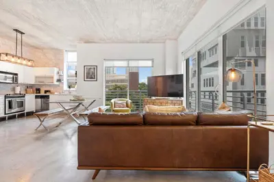 a living room with a brown couch and a kitchen at City Loft - Downtown Bayfront pool gym & parking in Miami