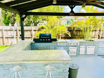 a outdoor kitchen with a grill in a backyard at Heated Pool Tropical House with Summer Kitchen 3BR- Oasis in Miami! in Miami