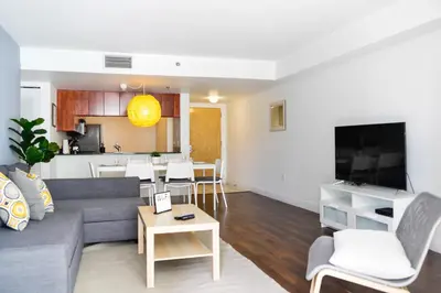 a living room with a gray couch and a kitchen at Amazing Condo Brickell with Ocean-Pool View in Miami