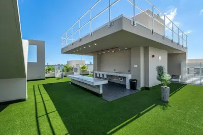 a house with a balcony on a green lawn at Stylish Apt with Pool and Gym near beach in Hollywood