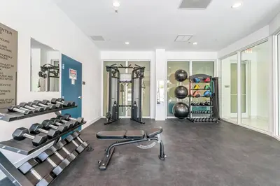 a gym with several treadmills and weights in a room at Stylish Apt with Pool and Gym near beach in Hollywood