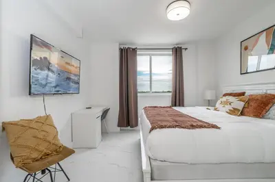 a white bedroom with a large bed and a window at Stylish Apt with Pool and Gym near beach in Hollywood