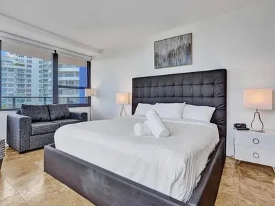 a bedroom with a large bed and a chair at Luxury Ocean View Condo Resort Amenities 501 in Miami Beach