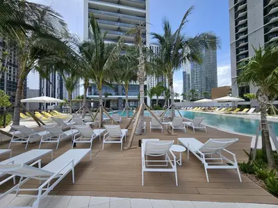a deck with chairs and a pool with palm trees at La Terrasse by VIAC - Luxury Bay View Studio with Balcony 29th Floor Miami in Miami