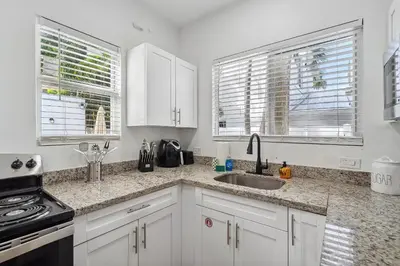 a kitchen with white cabinets and a sink and two windows at Casa Roselle # 2 in Hollywood