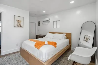 a white bedroom with a bed and a white chair at Casa Roselle # 3 in Hollywood