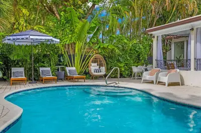a swimming pool with chairs and an umbrella at Miami Hidden Garden by TilahStays in Miami