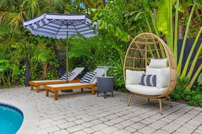 a patio with chairs and a swing next to a pool at Miami Hidden Garden by TilahStays in Miami