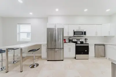 a kitchen with white cabinets and a stainless steel refrigerator at Beautiful Aventura Villa Sleeps 26 in Miami