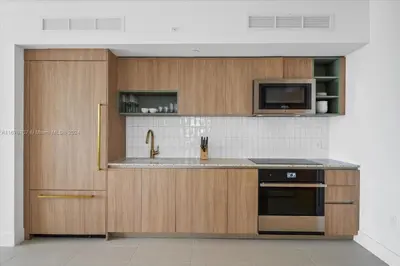 a kitchen with wooden cabinets and a sink and a microwave at Panoramic Ocean View 3 bedroom Nativo Pool Gym SPA in Miami