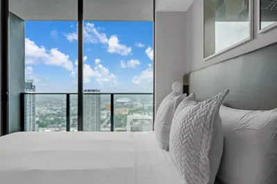 a bedroom with a white bed with a large window at Stylish City Getaway with Pool Skyline Views in Miami