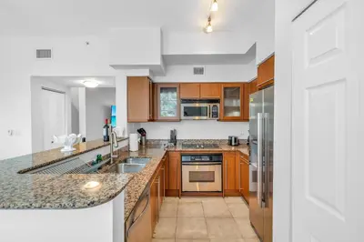 a kitchen with wooden cabinets and granite counter tops at Fantastic Townhouse Beach Access Resort Amenities! in Hallandale Beach