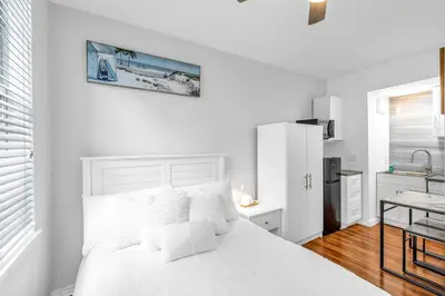 a white bedroom with a white bed and a kitchen at Fantastic Townhouse Beach Access Resort Amenities! in Hallandale Beach