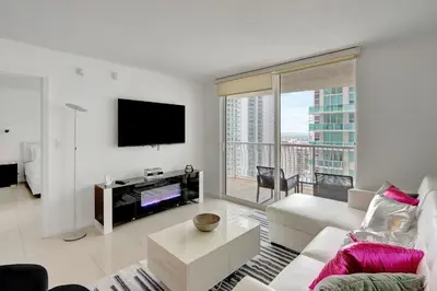 a living room with a white couch and a tv at Bay View Condo, Sleeps 6, Pool, Spa, Gym and Games in Miami