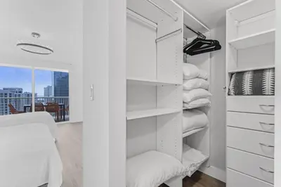 a white closet with white shelves and a chair at Curated Sky Abode Ocean and City views, Sleeps 6 in Miami