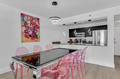 a kitchen with pink chairs and a glass table at Curated Sky Abode Ocean and City views, Sleeps 6 in Miami