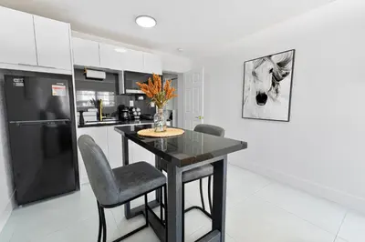 a kitchen with a black table and chairs and a refrigerator at Central King Studio Quiet & Close to Hard Rock in Miami Gardens