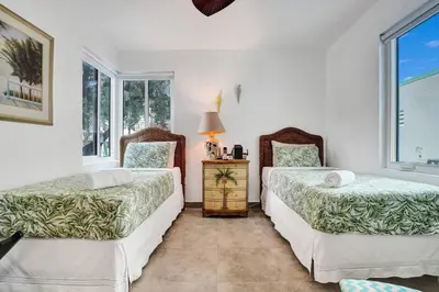 two beds in a room with two windows at Sunset Oceanfront Villa in Hollywood