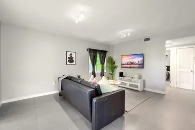 a living room with a leather couch and a window at Spacious East Miami Duplex Delightful in Miami