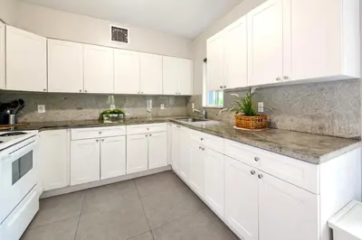 a white kitchen with white cabinets and a sink at Spacious East Miami Duplex Delightful in Miami