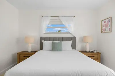 a bedroom with a large white bed with a window at Sunset Inn - Hallandale Beach in Hallandale Beach