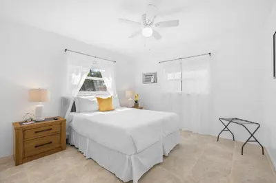 a white bedroom with a bed and a ceiling fan at Sunset Inn - Hallandale Beach in Hallandale Beach