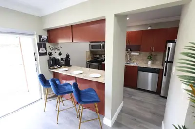 a kitchen with wooden cabinets and blue bar stools at Walk to Stadium - 3BR King Bed Haven - Parking in Miami Gardens