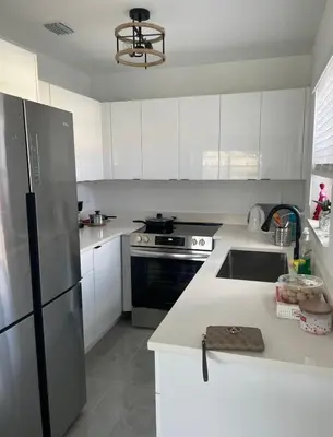 a kitchen with white cabinets and a stainless steel refrigerator at HOSTEL Star in Hallandale Beach