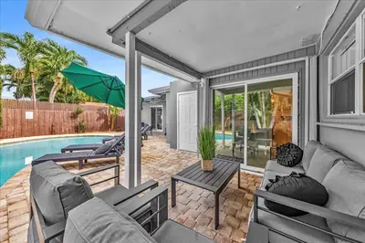 a patio with a couch and an umbrella and a pool at Sunny Days Getaway, 5BD Heated Pool Family Home! in Fort Lauderdale