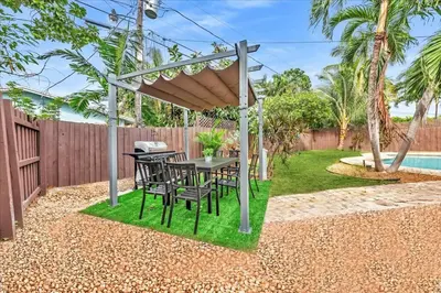 a patio with a table and chairs under a pergola at Sunny Days Getaway, 5BD Heated Pool Family Home! in Fort Lauderdale