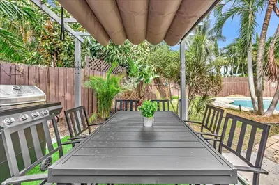 a black table with chairs and a grill in a backyard at Sunny Days Getaway, 5BD Heated Pool Family Home! in Fort Lauderdale