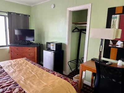 a bedroom with a bed and a desk and a television at Vacation Inn motel - FT Lauderdale Airport and Cruise port in Fort Lauderdale