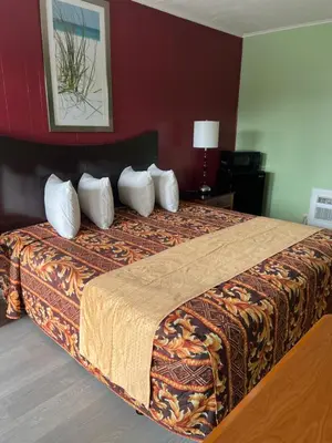 a hotel room with a bed with four pillows at Vacation Inn motel - FT Lauderdale Airport and Cruise port in Fort Lauderdale