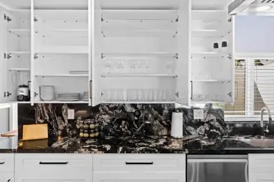 a kitchen with white cabinets and a black counter top at Spacious 4BR Waterfront Home with Private Pool, Tiki Hut & Free Parking near Miami & Key Largo in Cutler Bay