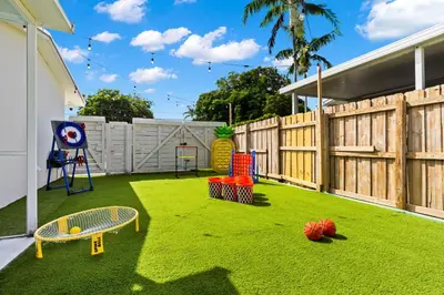 a backyard with a play yard with a wooden fence at Spacious 4BR Waterfront Home with Private Pool, Tiki Hut & Free Parking near Miami & Key Largo in Cutler Bay