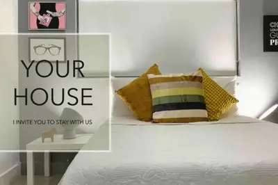 a bedroom with a white bed with a yellow pillow at GroveO1 10 min from the beach in Miami