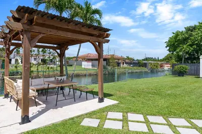 a wooden gazebo with a table and chairs in a yard at Casa Cabos - Fun in Miami - Pool BBQ - Fit 10 in Tamiami
