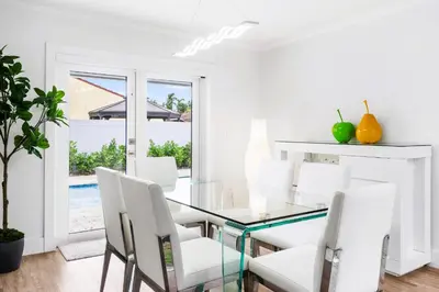 a dining room with a glass table and white chairs at Gables Paradise - Htd Pool,5 Bdrooms ,Mini Golf, Playground, Baby Items, BBQ in Tamiami