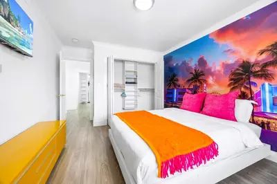 a bedroom with a large bed with pink and orange pillows at Gables Paradise - Htd Pool,5 Bdrooms ,Mini Golf, Playground, Baby Items, BBQ in Tamiami