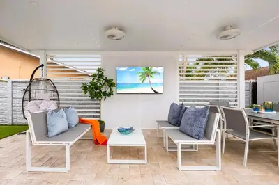 a patio with chairs and a table with a picture on the wall at Gables Paradise - Htd Pool,5 Bdrooms ,Mini Golf, Playground, Baby Items, BBQ in Tamiami