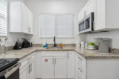 a white kitchen with white cabinets and a sink at Casa Roselle On The Beach Full 22 in Hollywood