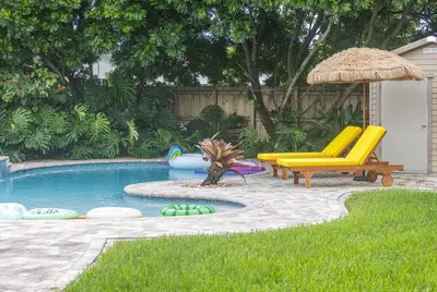 a backyard with a pool with a chair and an umbrella at Casa Mexican home - Big Pool - Hot Tub - FITS 12 in Miami